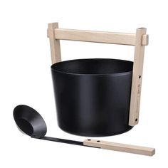 a black pot and ladle sitting on top of a white surface next to a wooden holder