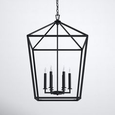 a black lantern hanging from the ceiling with four candles in it and one light on each side