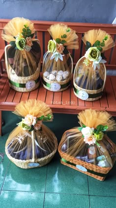 four vases with flowers in them sitting on a wooden bench next to each other