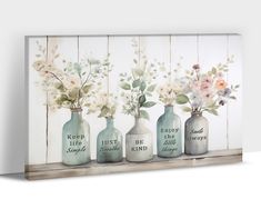 three vases with flowers are sitting on a shelf in front of a white wall