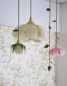 three flowers hanging from the ceiling in front of a floral wallpapered room with white walls