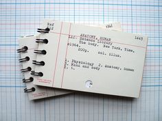 two notebooks sitting next to each other on top of a sheet of lined paper