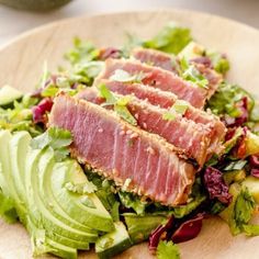 a wooden plate topped with sliced meat and veggies on top of lettuce