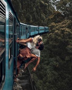 two people climbing up the side of a train