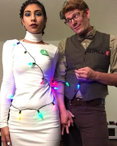 a man and woman dressed in costumes with christmas lights on their body, standing next to each other