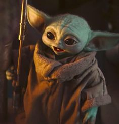 the child yoda from star wars is holding a stick and looking at the camera