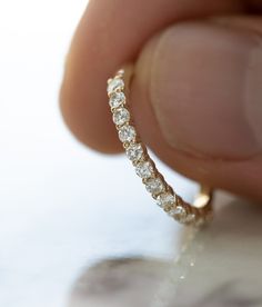 a close up of a person's hand holding a diamond ring in front of the camera