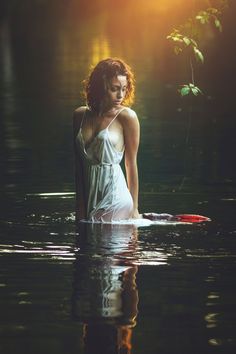 a woman is sitting on a surfboard in the water with her back to the camera