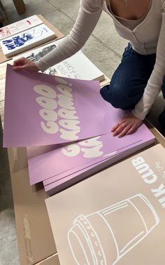 a woman sitting on the floor next to some cardboards and signs that say i love my cup