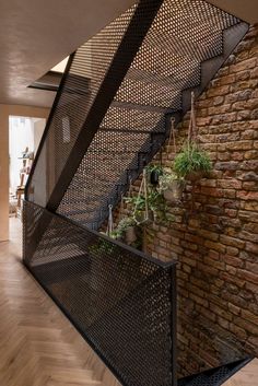 an iron stair case with potted plants on the side and brick wall behind it