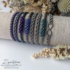 several bracelets are stacked on top of each other in different colors and sizes, along with dried flowers