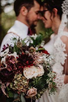 the bride and groom are standing close to each other with their wedding bouquet in front of them