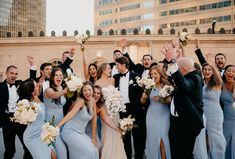 a group of people standing next to each other in front of a building holding bouquets