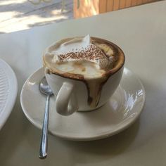 a cappuccino on a saucer next to a spoon