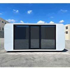 a small white building with black doors in the middle of an empty lot next to buildings