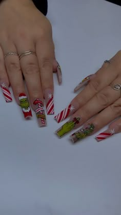 two hands with christmas themed nail polishes on their fingers and one hand holding candy canes