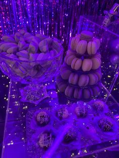 purple desserts and candies are on display in front of the party lights at this event