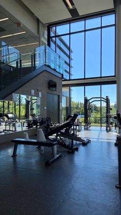 an empty gym with many machines in the center and large windows on the side wall