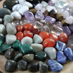 many different colored rocks on a wooden plate