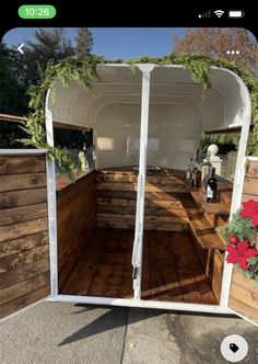 the inside of a horse trailer with wooden floors and walls, decorated with greenery