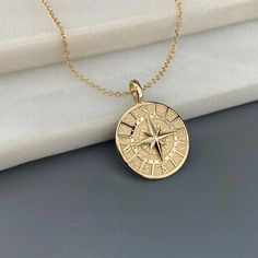 a gold necklace with a compass on it