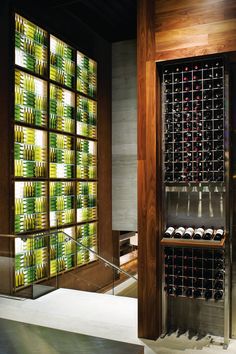 a wine cellar filled with lots of bottles next to a glass wall covered in lights