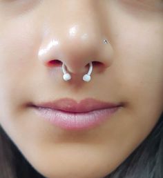 a close up of a woman's nose with two piercings on her nose