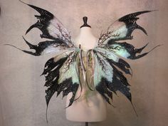 a white mannequin with black and green butterfly wings on it's head