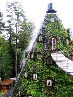 a very unusual house made out of plants and water spouting from the roof