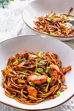 two white bowls filled with noodles and meat