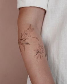 a woman's arm with flowers on it and a small tattoo design on the arm