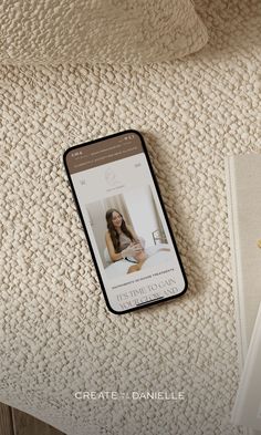 a cell phone sitting on top of a bed next to a book