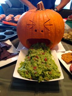 a pumpkin sitting on top of a plate with guacamole