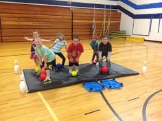 children playing with balls on an indoor gym floor in the middle of a play area