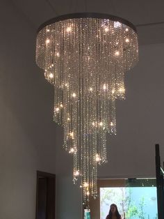 a woman standing under a chandelier in a room