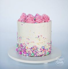 a white cake with pink frosting and sprinkles