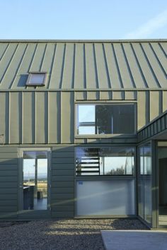 an exterior view of a modern house with large windows and metal siding on the roof