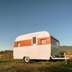 an old camper trailer is parked in a field