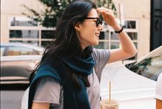 a woman walking down the street with a drink in her hand