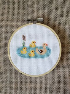 a cross stitch pattern with three ducks in the water and one duckling is swimming