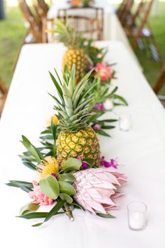 pineapples and flowers are lined up on a long table