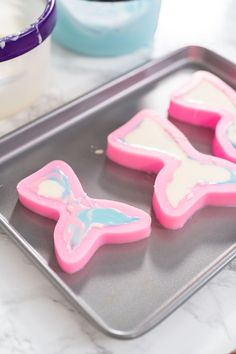 three decorated cookies sitting on top of a cookie sheet in front of a cup and saucer