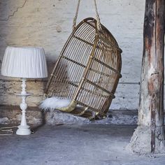 a rattan hanging chair next to a lamp on the floor in an old room