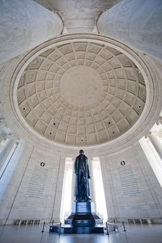 the inside of a white building with a statue in it's center and windows