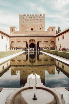 a large building with a pool in front of it and lots of people standing around