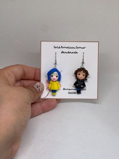 someone is holding up two earrings with the same character on them in front of a white background