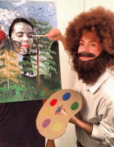 a man with an afro wig and beard holding a paint palette in front of his face