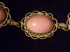 "An elegant Czehoslovakian choker necklace in the Victorian style. Five glass coral cabochons with lacy gilt filigree settings look like real, delicate colored salmon coral pieces. The links between the coral pieces are also elaborate with decoration. A charming costume jewelry necklace from the last century. Dimensions: approx. length 14 1/4\" (36.20cm ) width 3/4\" (1.91cm) Weight: approx. 1.10 oz, 31.16 g Metal: gilt Gemstone: glass--faux coral cabochons Style: choker, Victorian style Age: ea Formal Coral Jewelry With Cabochon Details, Formal Coral Jewelry With Cabochon, Vintage Oval Coral Jewelry, Vintage Coral Oval Jewelry, Coral Cabochon Jewelry For Gift, Formal Pink Cabochon Necklace, Vintage Coral Jewelry For Wedding, Coral Vintage Jewelry For Wedding, Small Pearl Ring