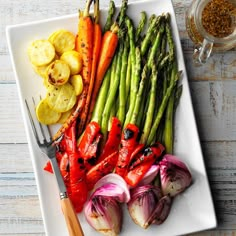 a white plate topped with asparagus, carrots and other vegetables