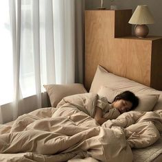 a young child is sleeping in a bed with sheets and pillows on top of it